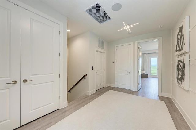 hallway featuring visible vents, light wood finished floors, and an upstairs landing