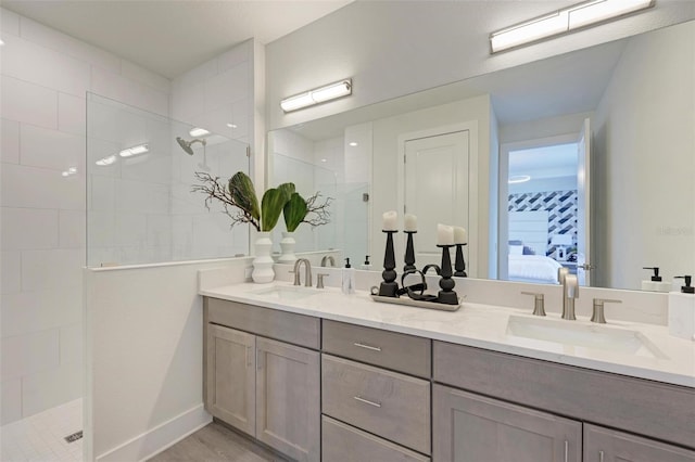 ensuite bathroom featuring a walk in shower, double vanity, ensuite bath, and a sink