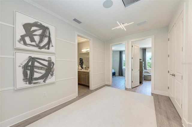 corridor featuring light wood finished floors, baseboards, and visible vents