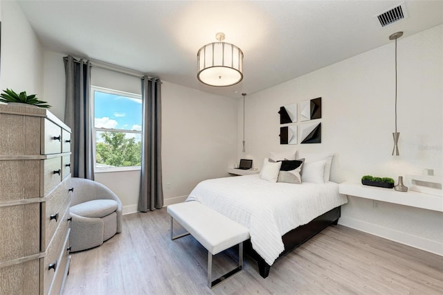 bedroom with wood finished floors, visible vents, and baseboards