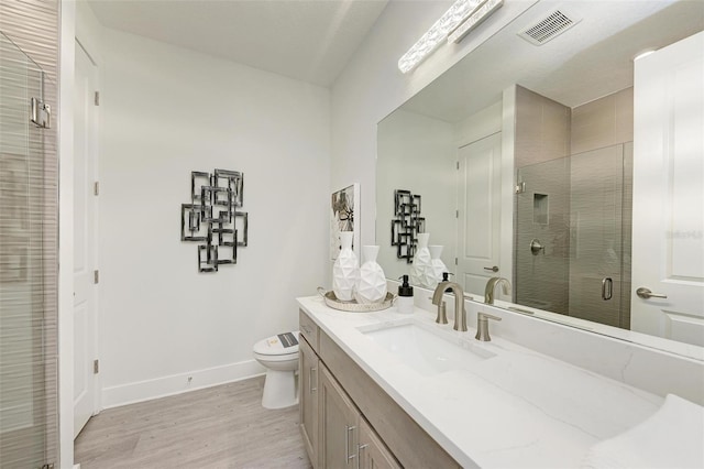 full bath with visible vents, a stall shower, vanity, wood finished floors, and baseboards