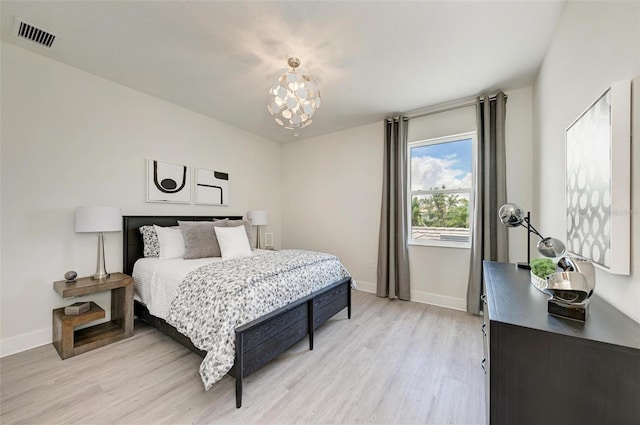 bedroom featuring light wood-type flooring, visible vents, baseboards, and a chandelier