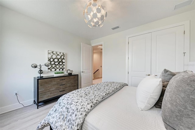 bedroom with light wood-style flooring, a closet, visible vents, and baseboards