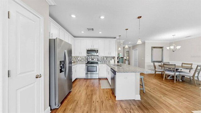 kitchen with a breakfast bar, a peninsula, stainless steel appliances, white cabinetry, and a sink