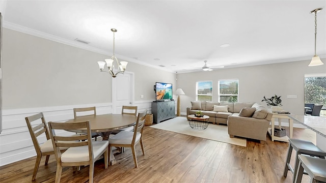 dining area with a wealth of natural light, visible vents, light wood finished floors, and crown molding