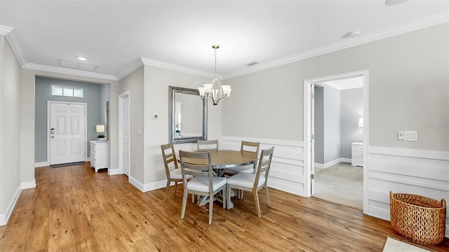 dining area with visible vents, light wood-style flooring, crown molding, baseboards, and a chandelier