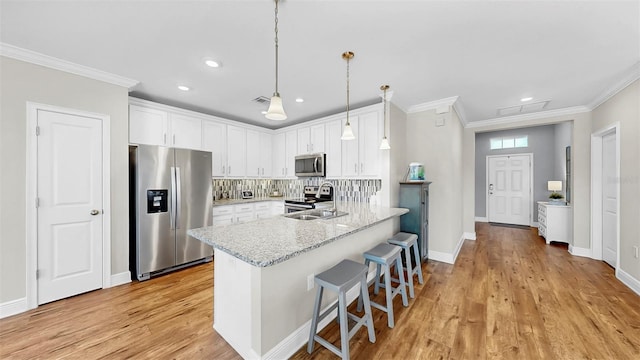 kitchen featuring a sink, stainless steel appliances, a peninsula, white cabinets, and crown molding