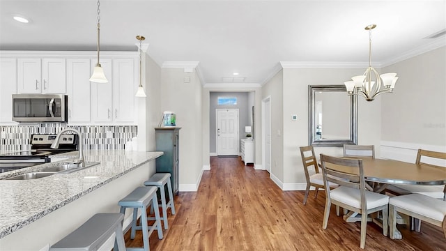 kitchen featuring light wood-style flooring, a sink, tasteful backsplash, white cabinetry, and stainless steel appliances