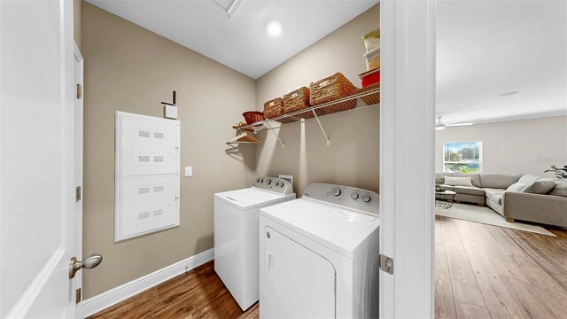 clothes washing area with washer and clothes dryer, laundry area, baseboards, and wood finished floors