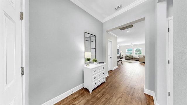 corridor featuring dark wood finished floors, crown molding, baseboards, and visible vents