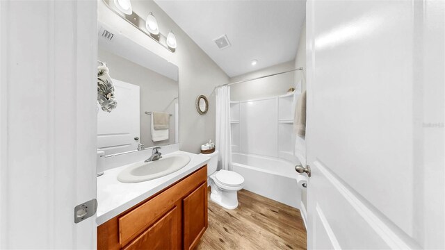 bathroom with visible vents, toilet, shower / bath combo with shower curtain, wood finished floors, and vanity