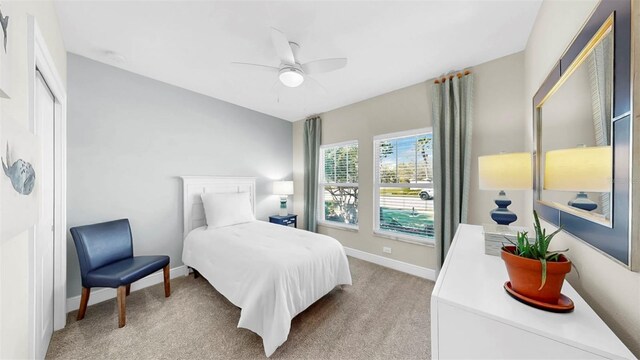 bedroom featuring light colored carpet, baseboards, and ceiling fan