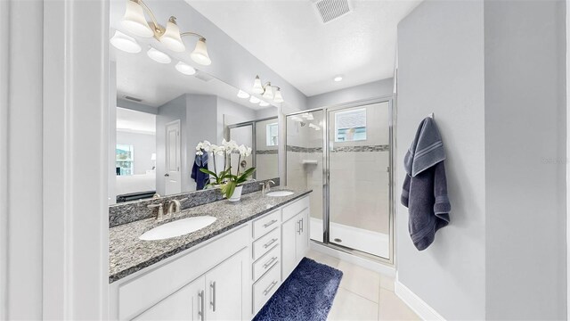 ensuite bathroom with a sink, visible vents, a healthy amount of sunlight, and tile patterned floors