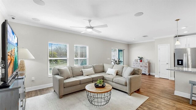 living room with baseboards, recessed lighting, ceiling fan, light wood-style floors, and crown molding