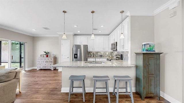 kitchen with visible vents, a peninsula, a sink, white cabinets, and appliances with stainless steel finishes