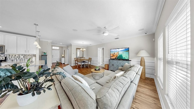 living room with a ceiling fan, crown molding, light wood-style floors, and visible vents