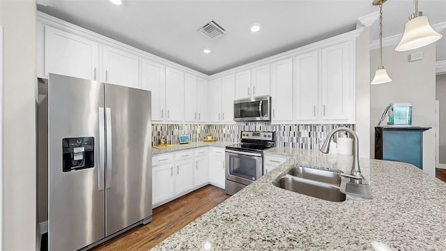 kitchen featuring light stone counters, visible vents, a sink, appliances with stainless steel finishes, and backsplash