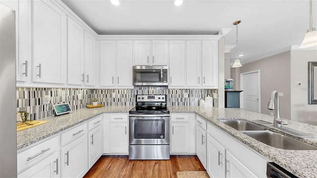 kitchen featuring backsplash, light wood-style flooring, appliances with stainless steel finishes, white cabinets, and a sink