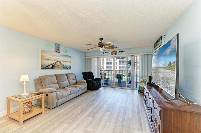 living room with light wood-style flooring, a ceiling fan, and a textured ceiling