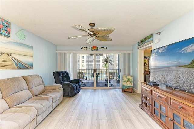 living area featuring light wood-style flooring, ceiling fan, and a textured ceiling
