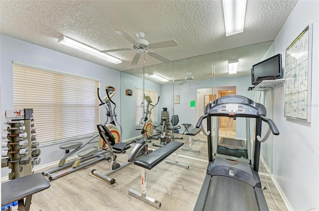 gym featuring a textured ceiling, wood finished floors, a ceiling fan, and baseboards