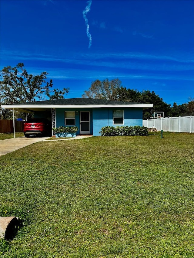 ranch-style house with a carport, concrete driveway, fence, and a front lawn