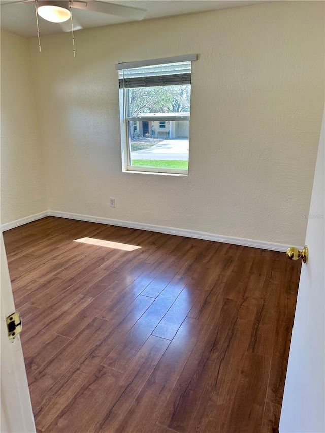 spare room featuring a ceiling fan, baseboards, wood finished floors, and a textured wall