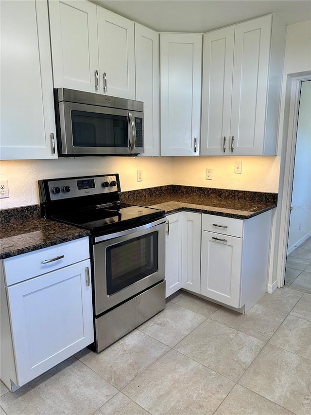 kitchen featuring appliances with stainless steel finishes, white cabinets, and dark stone countertops