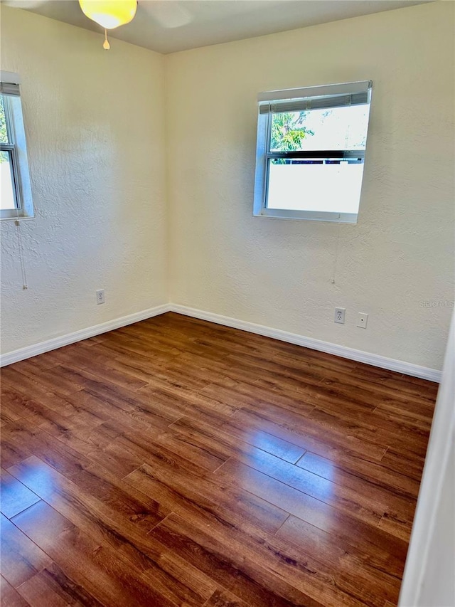 spare room with hardwood / wood-style flooring, plenty of natural light, and baseboards