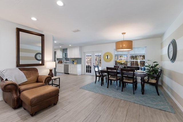 dining space featuring light wood-type flooring, visible vents, a wealth of natural light, and french doors