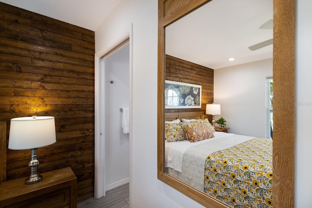 bedroom with recessed lighting, wooden walls, and wood finished floors