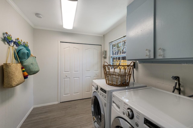 washroom featuring light wood finished floors, washer and clothes dryer, cabinet space, and baseboards