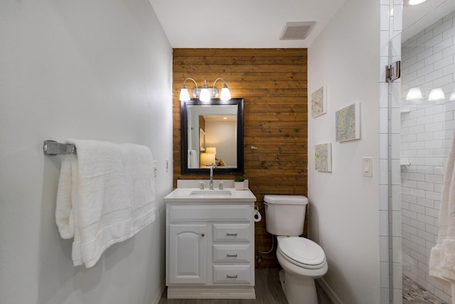 full bath with wood walls, visible vents, a tile shower, and vanity