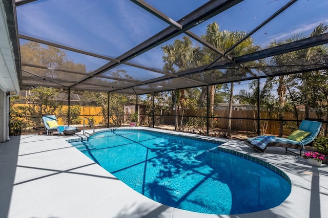 view of swimming pool featuring glass enclosure, a fenced backyard, a fenced in pool, and a patio