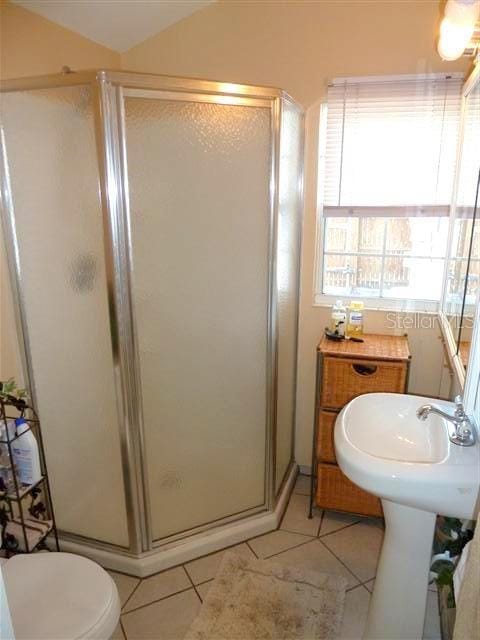 full bathroom with vaulted ceiling, a stall shower, toilet, and tile patterned floors