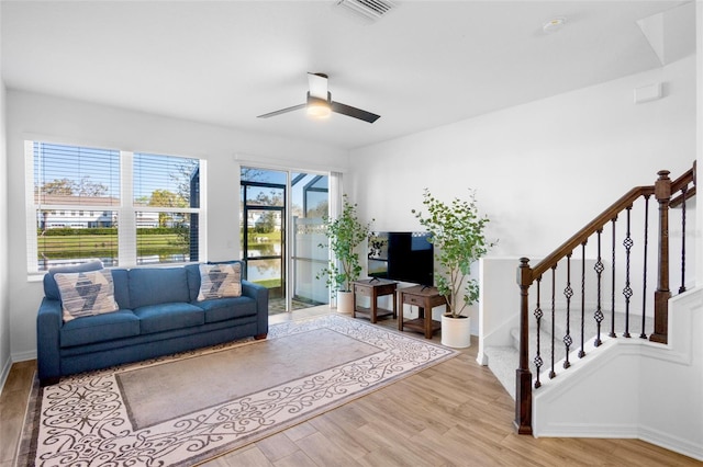 living area featuring stairs, ceiling fan, wood finished floors, and visible vents