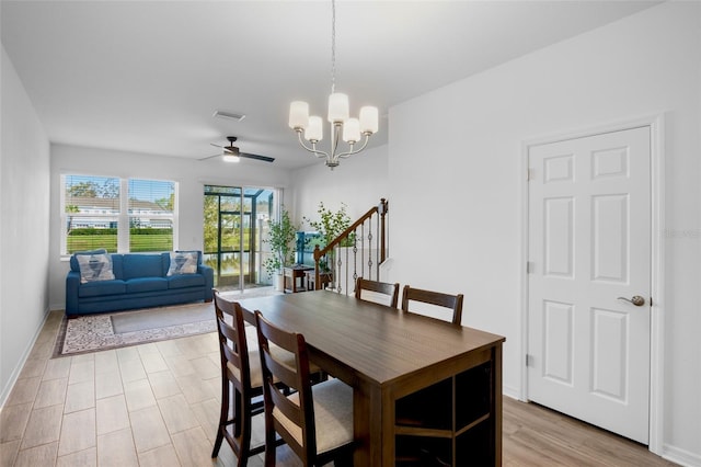 dining room with ceiling fan with notable chandelier, visible vents, baseboards, stairway, and light wood finished floors