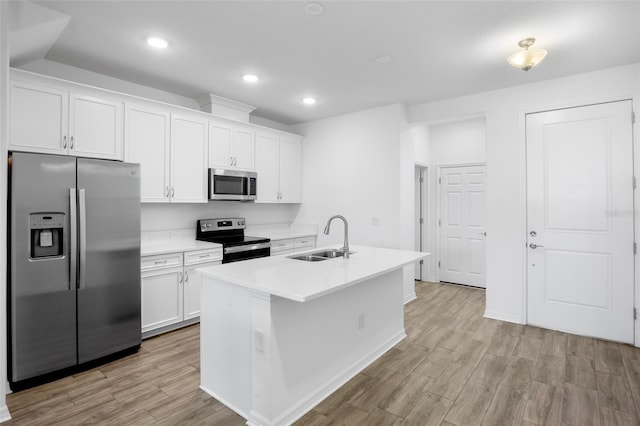 kitchen featuring stainless steel appliances, light wood-type flooring, a sink, and white cabinetry