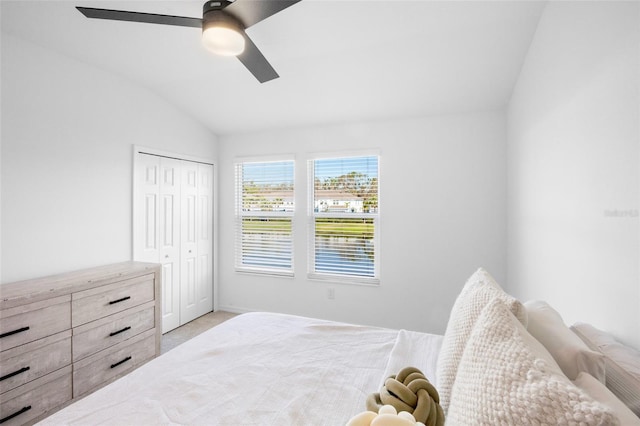 bedroom featuring vaulted ceiling, ceiling fan, a closet, and light carpet