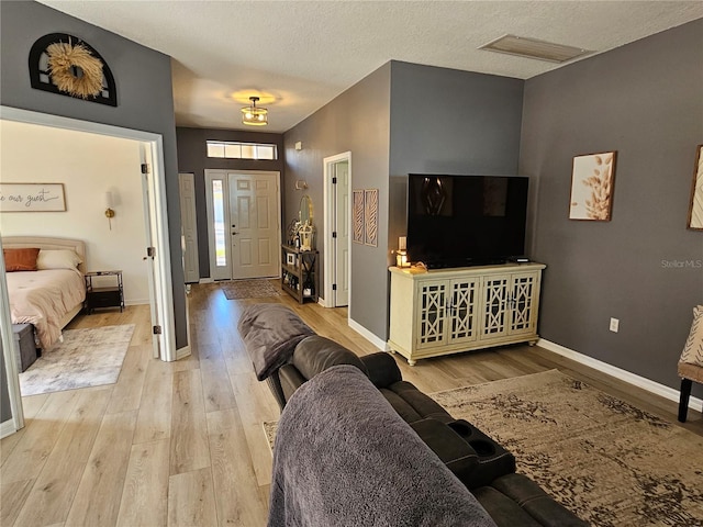 entrance foyer with a textured ceiling, light wood-style flooring, visible vents, and baseboards