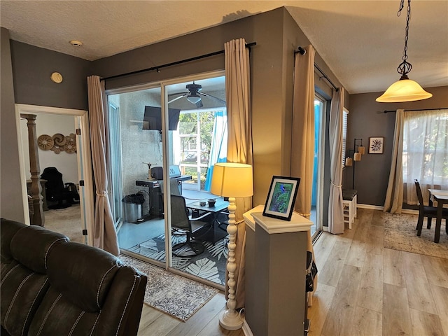 interior space with a textured ceiling, light wood-style flooring, and baseboards