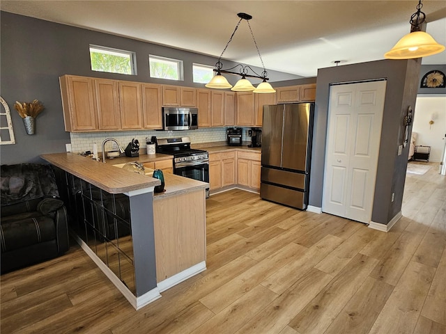 kitchen featuring a peninsula, appliances with stainless steel finishes, a breakfast bar, and pendant lighting