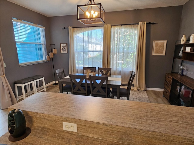 dining room with a chandelier, a wealth of natural light, light wood-style flooring, and baseboards