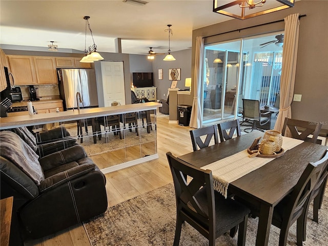 dining space featuring visible vents, light wood-style flooring, and a ceiling fan