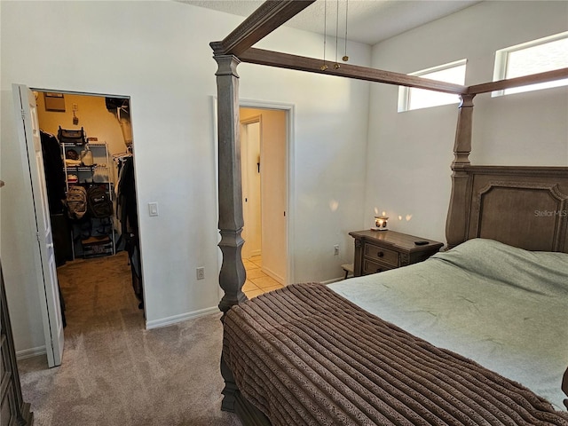 bedroom featuring light carpet, baseboards, a walk in closet, and a closet