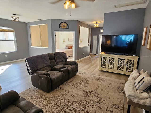 living room featuring ceiling fan, light wood-type flooring, and baseboards