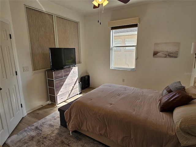 bedroom featuring light wood finished floors, baseboards, and a ceiling fan