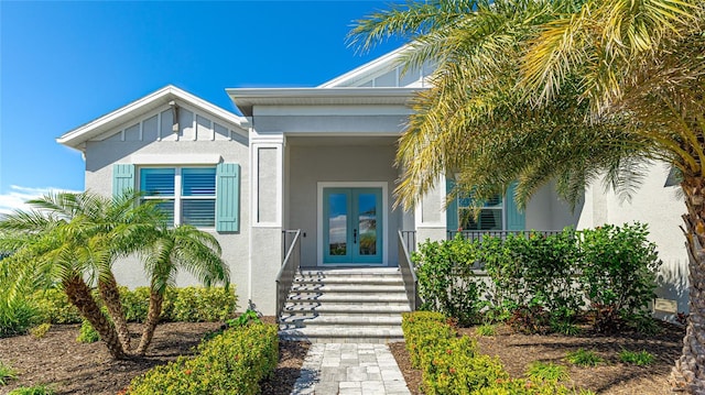 property entrance featuring french doors, board and batten siding, and stucco siding