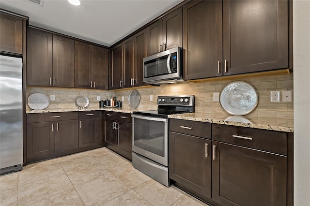 kitchen with light tile patterned floors, stainless steel appliances, dark brown cabinets, light stone countertops, and tasteful backsplash