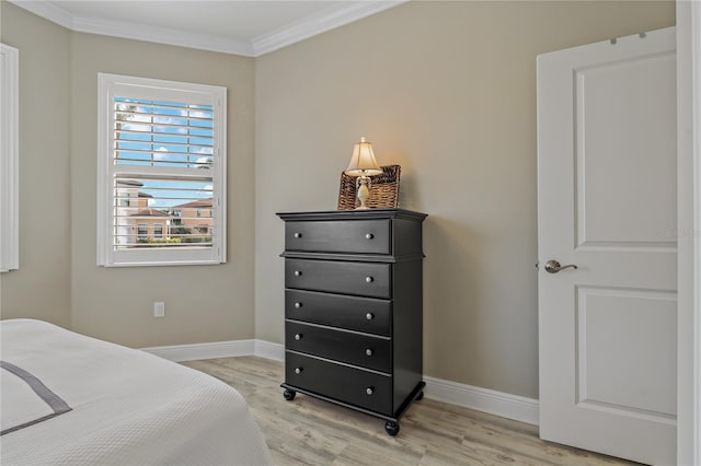 bedroom featuring ornamental molding, light wood-type flooring, and baseboards